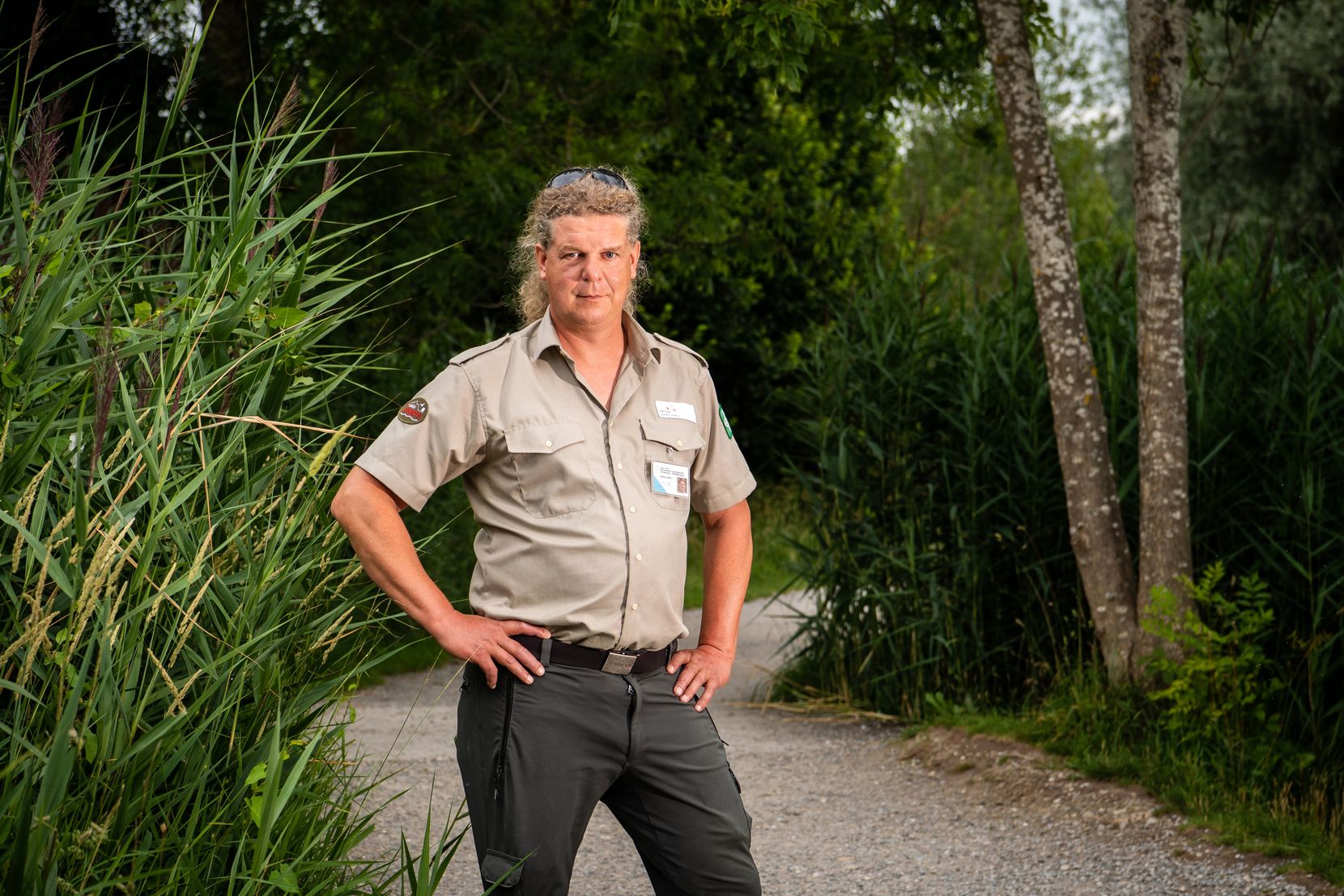 Ein Mann steht mit in die Hüften gestemmten Armen auf einem Weg.